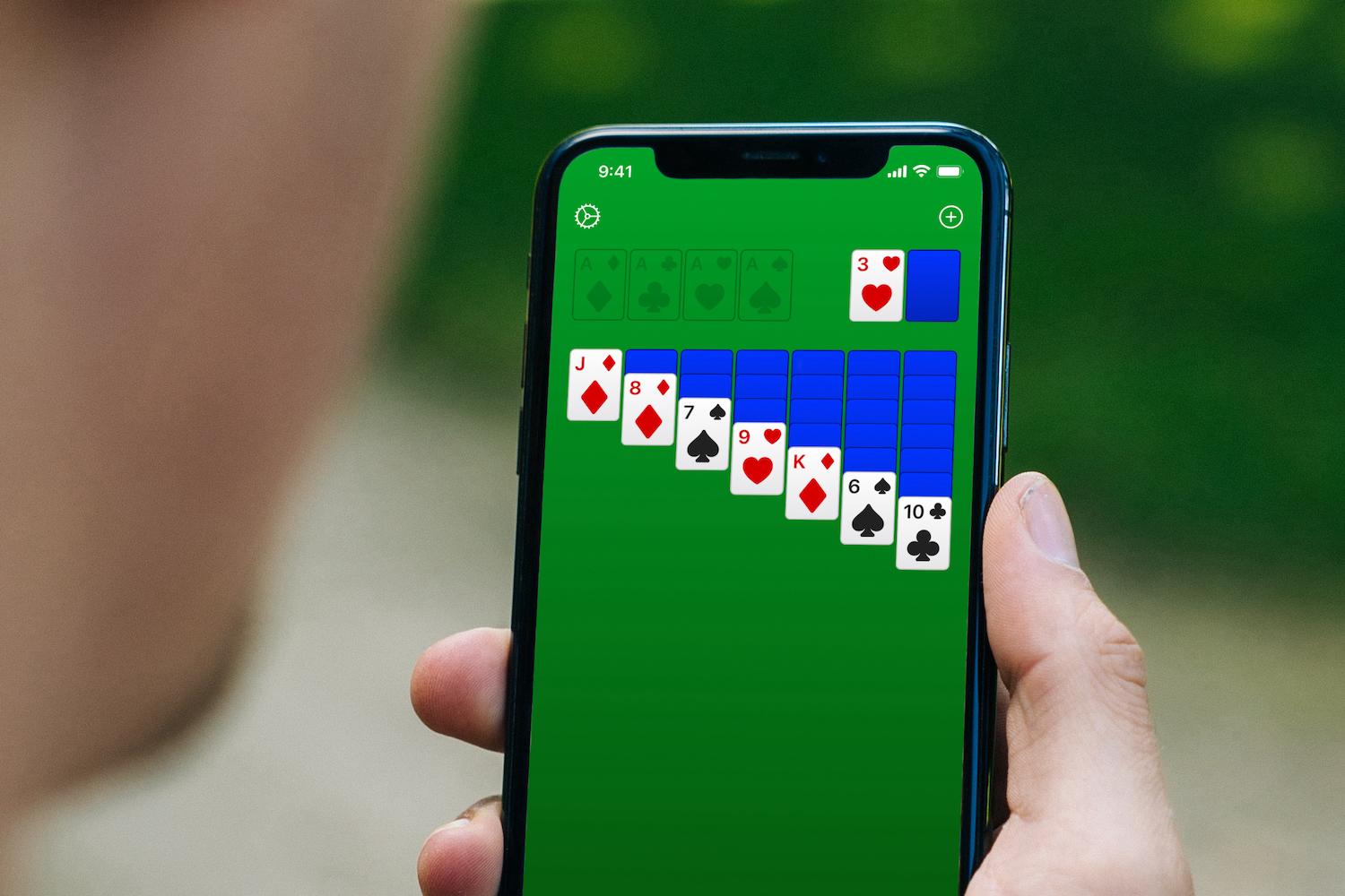 Hand holding an iPhone with Solitaire open